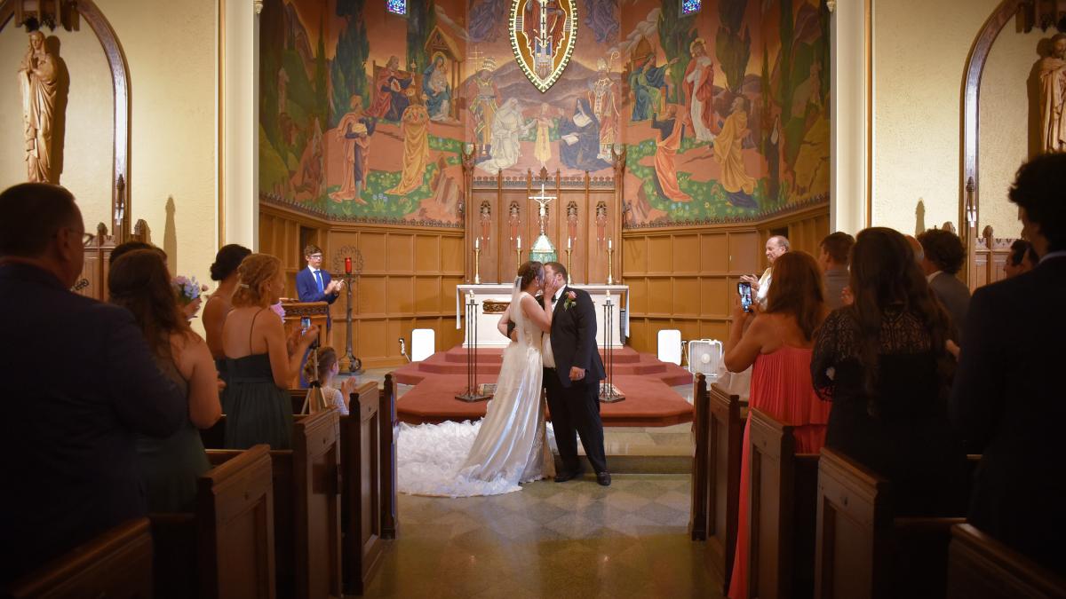 a bride and groom at the altar in christ the king chapel