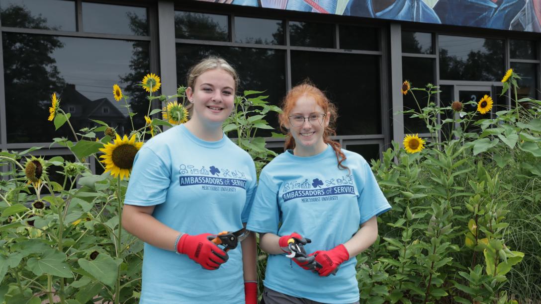 two female students pose while gardening